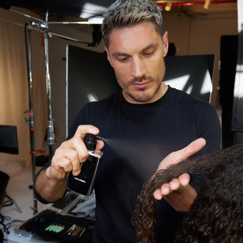Stylist Chris Appleton spritzing Extra Strength Dream Coat on coily hair