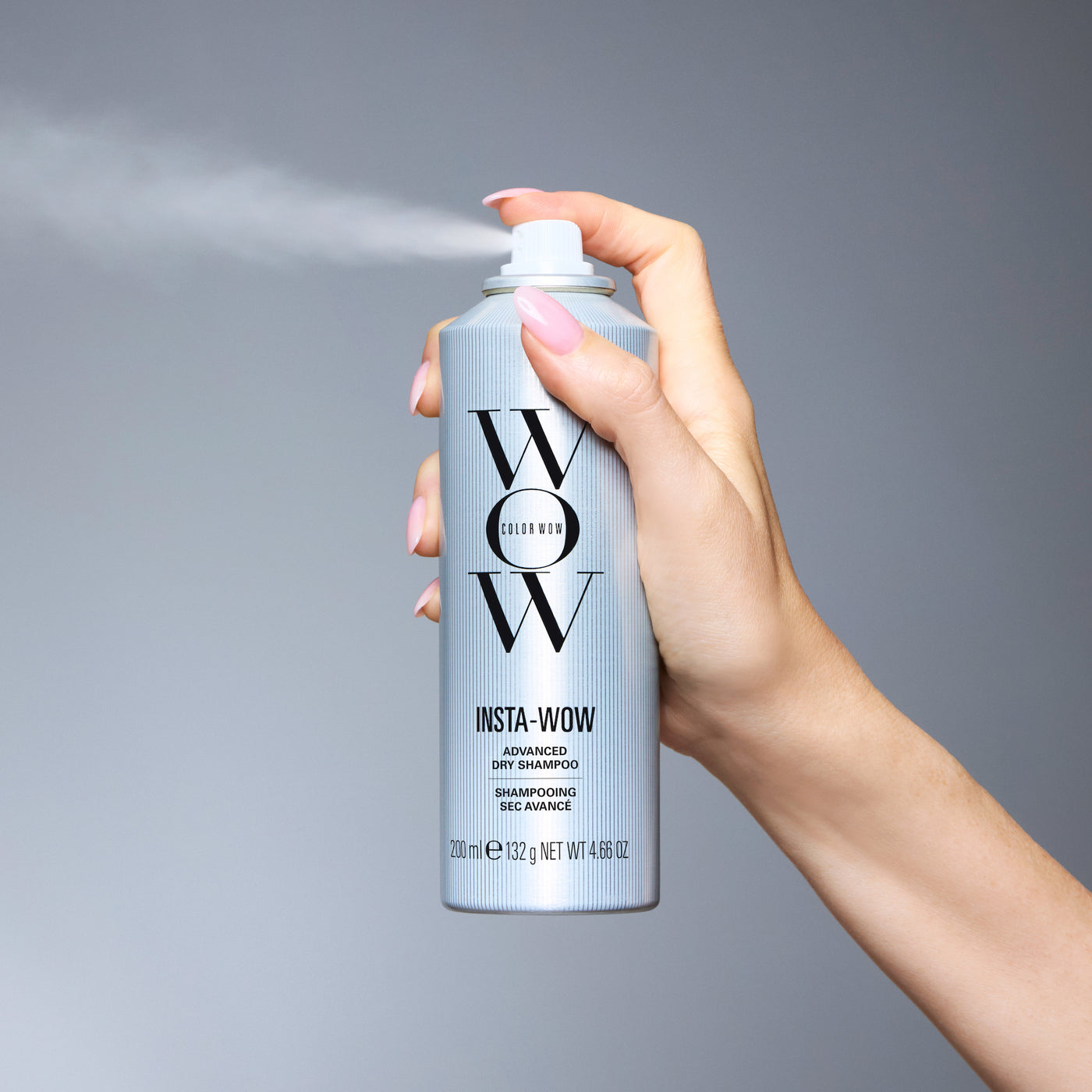 Hand holding Color Wow Insta-WOW Advanced Dry Shampoo against a grey background