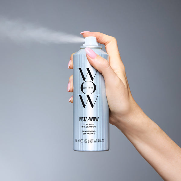 Hand holding Color Wow Insta-WOW Advanced Dry Shampoo against a grey background